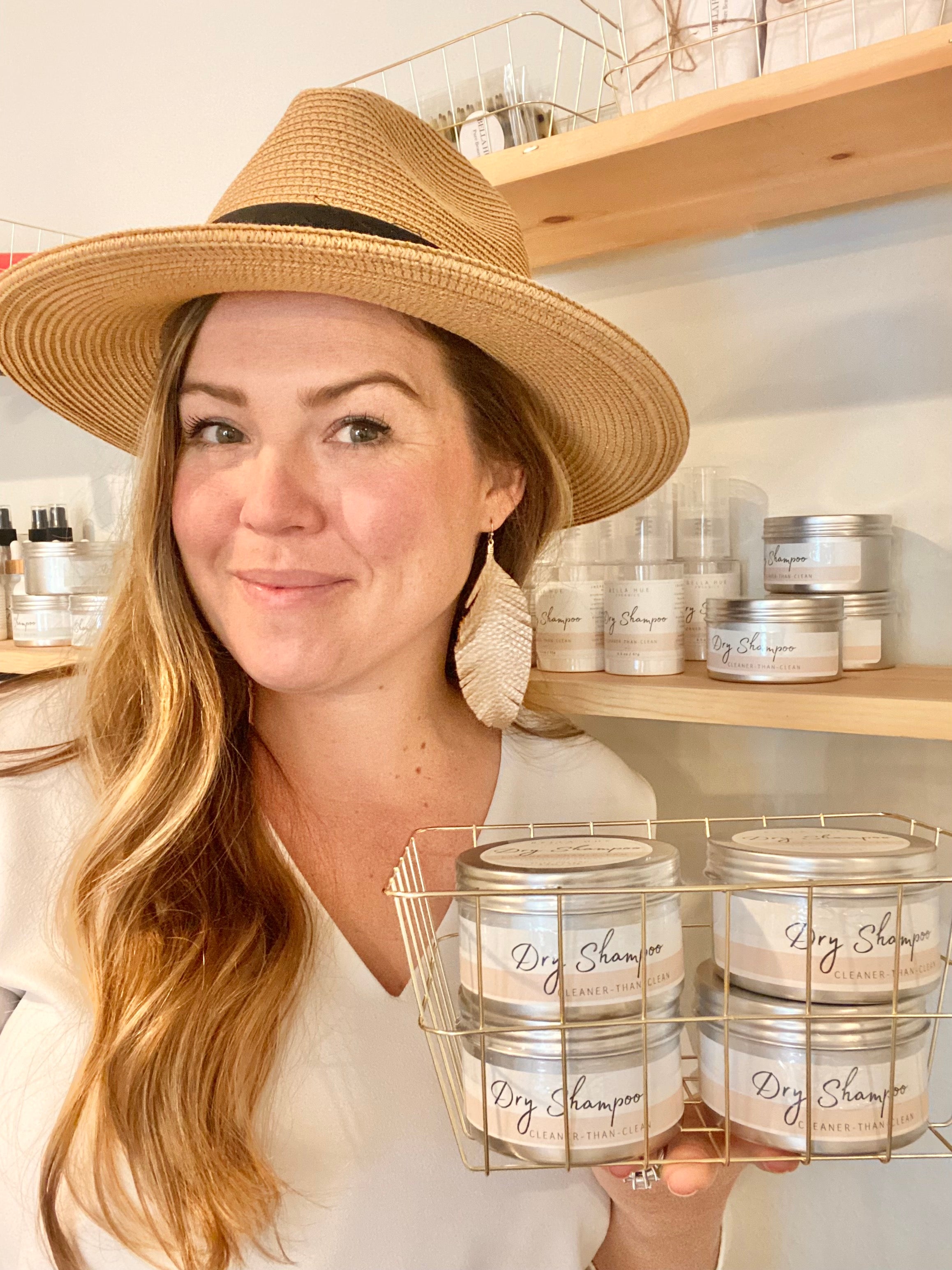 Founder and master stylist Lauren wearing neutral colors, holding a wire basket of tin containers.